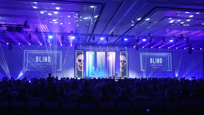 Wide shot of Chad E Foster presenting at CCW Vegas conference with Blind Ambition branding