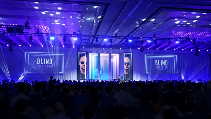 Chad E Foster on conference stage with professional lighting and presentation screens
