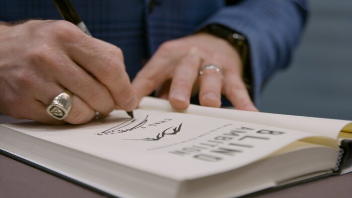 Chad E Foster at book signing table with Blind Ambition books at Vegas CCW