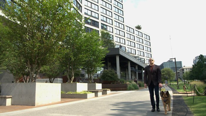 Chad E Foster walking confidently past modern building, showing independence and mobility